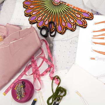 A variety of cloth, ribbon and designs on a worktable.